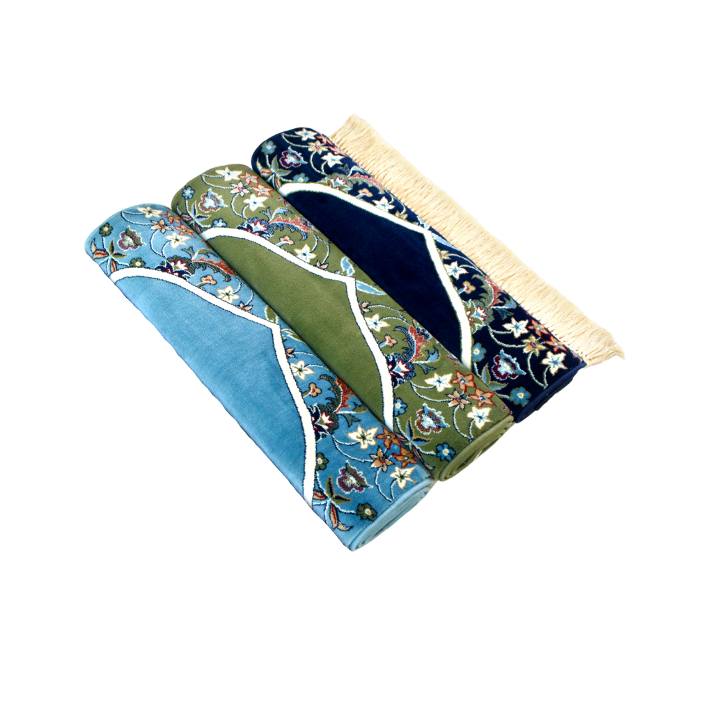 Three Imam Al Haram prayer mats displayed together: dark blue, green, and sky blue, each featuring intricate patterns and rich textures.